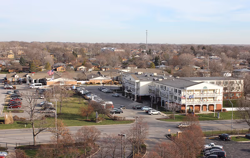 Aerial view of the Rosewalk at Lutherwoods senior living building, its parking lot, and the surrounding neighborhood.