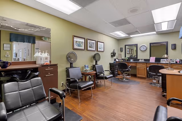 Salon-style interior with styling chairs, hair dryers, mirrors, and workstations.