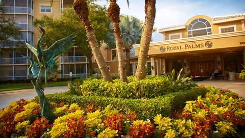 Entrance to Royal Palms senior living with palm trees and colorful landscaping.