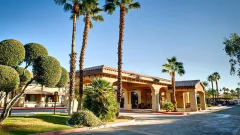 Exterior view of Atria Hacienda, a senior living facility, with palms and a covered entrance.
