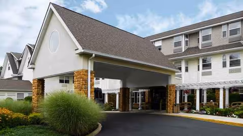 Exterior view of Atria Tinton Falls senior living facility with a covered entrance and landscaped driveway.