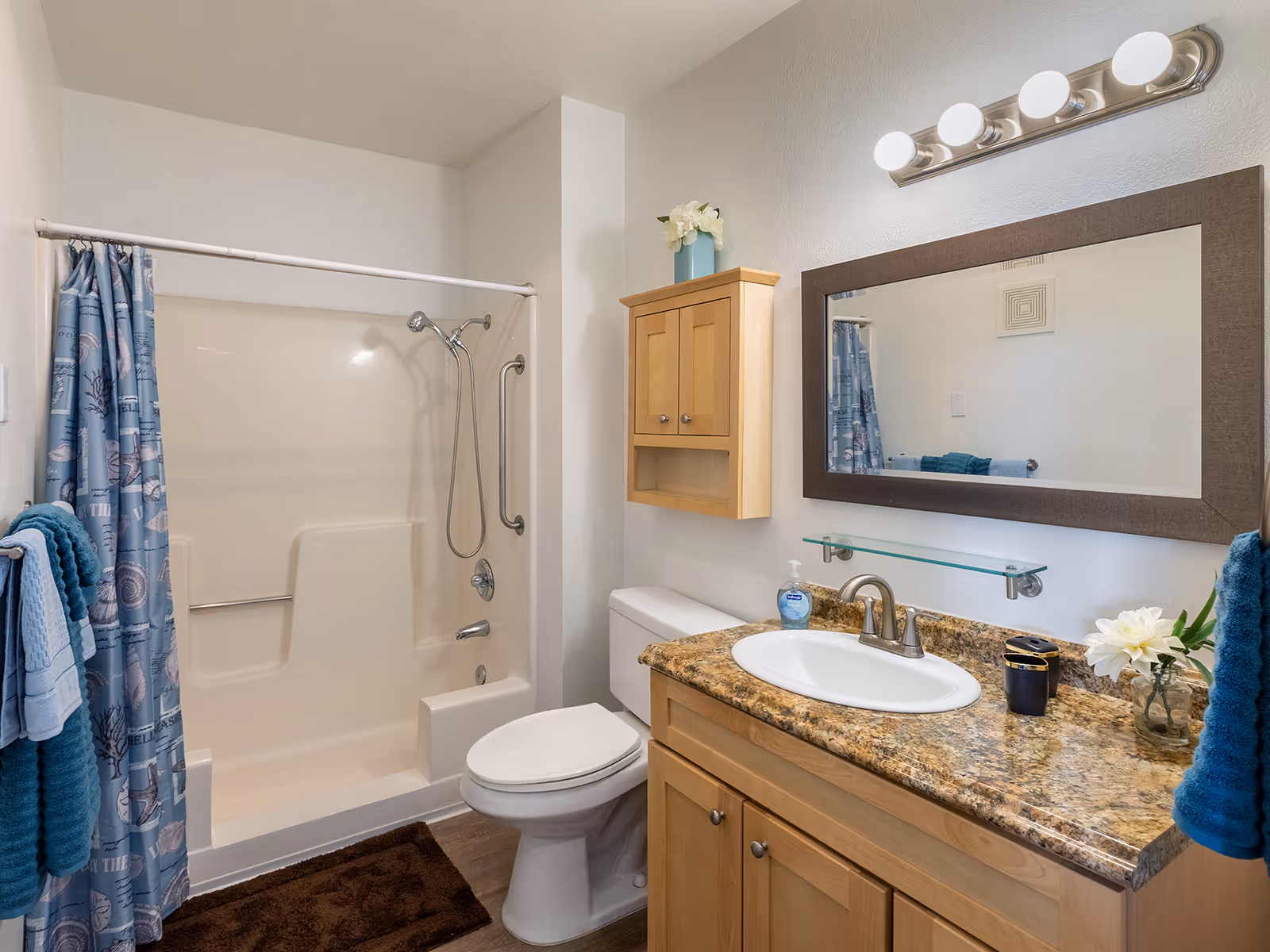 Bathroom with a tub/shower, toilet, and a vanity with a granite countertop, mirror, and towels.