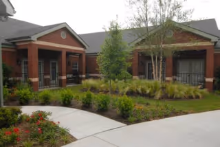 Brick single-story building with covered porches around a landscaped courtyard and concrete walkways.