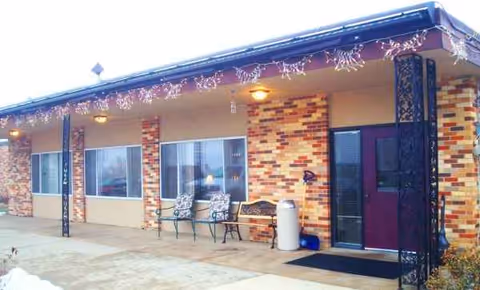Front exterior of Parkview Manor with brick columns, string lights, and outdoor seating.