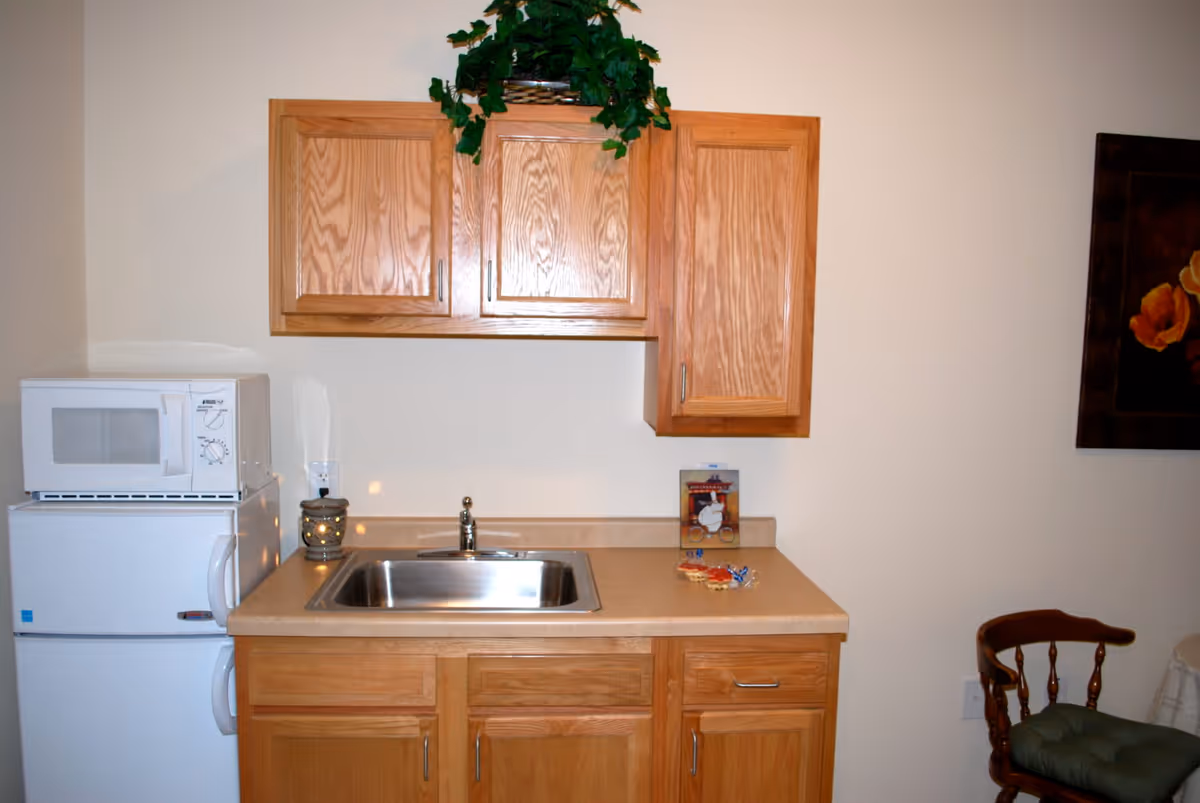 Small kitchenette with a sink, wooden cabinets, microwave, and mini refrigerator.