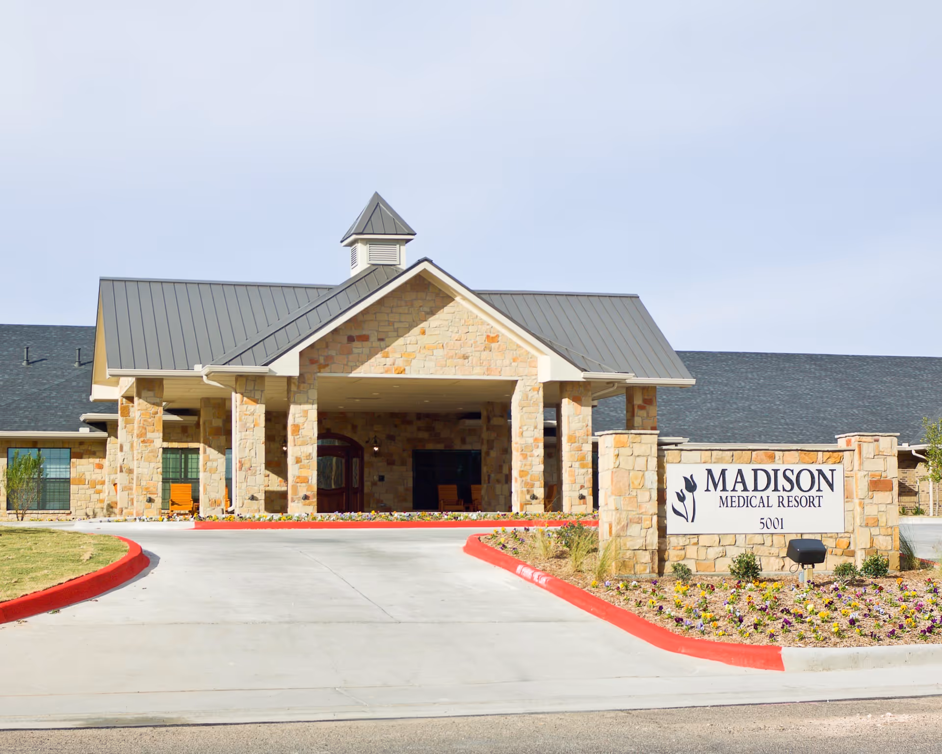 Stone building's covered main entrance and driveway with a sign reading 'Madison Medical Resort'.