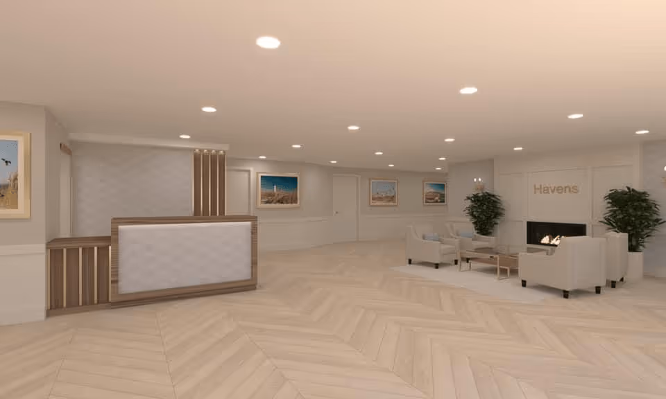Bright, modern assisted-living lobby with a reception desk and a seating area around a fireplace labeled "Havens".