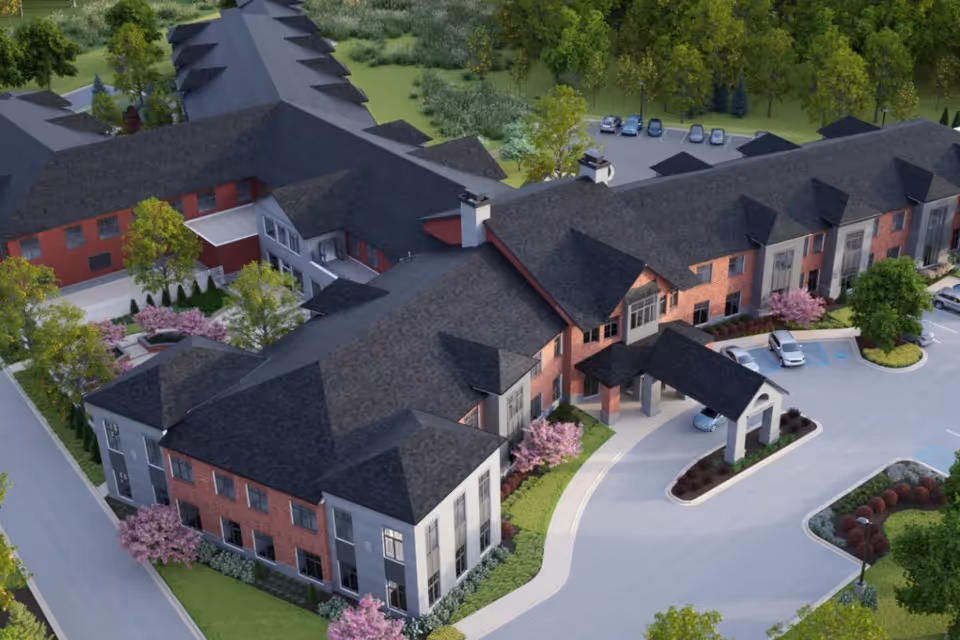 Aerial view of a brick senior living campus with connected buildings and parking.