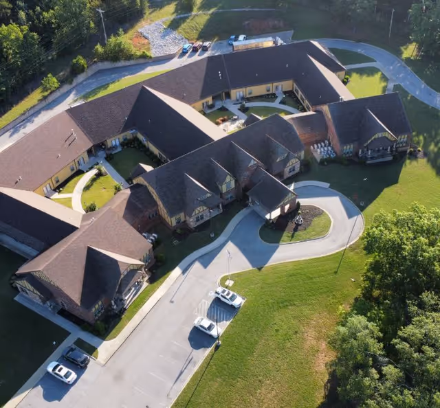 Aerial view of a multi-wing senior living campus with driveways and parked cars.