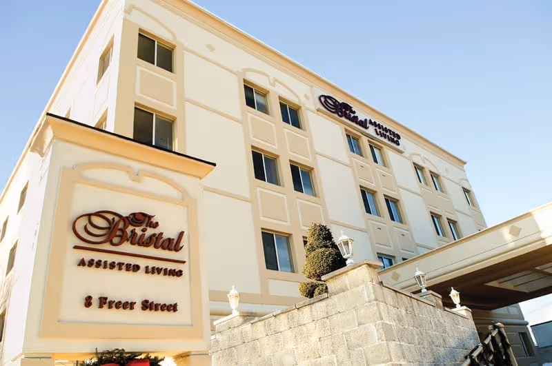 Exterior view of The Bristal Assisted Living building with a prominent entrance sign reading 'The Bristal Assisted Living 8 Freer Street'.