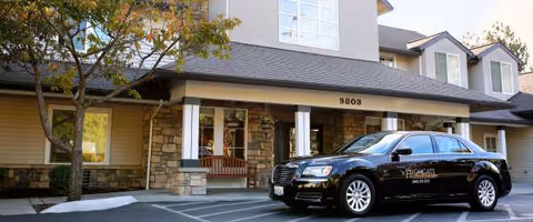 Front of Highgate Senior Living building with entrance porch and a black car.