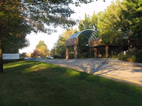 Exterior view of Gurwin facility entrance with a curved green canopy and trees.