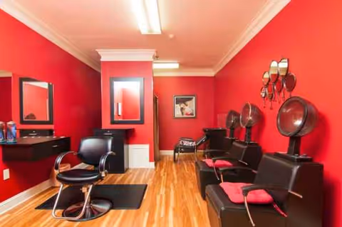 Stylish red-walled senior living salon with chairs, mirrors, and hair styling equipment.