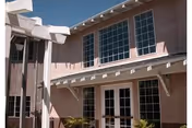 Pink stucco two-story building exterior with large windows and white awnings.