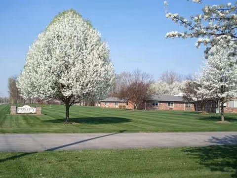 Front view of Twin City Health Care building with a green lawn and blooming trees.