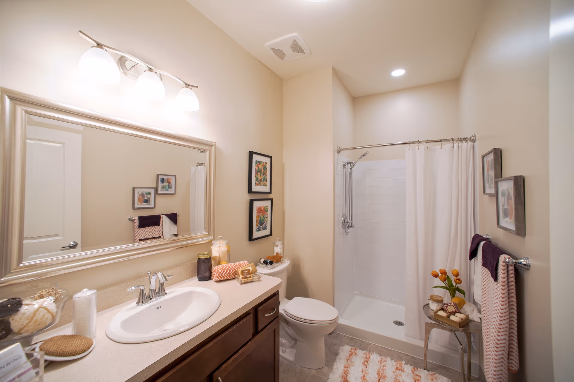 Bright, modern bathroom featuring a vanity with sink and large mirror, a toilet, and a shower with a curtain.