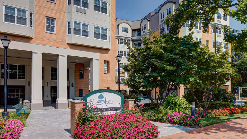 Exterior view of Atria Park of Great Neck with entrance and landscaped surroundings.