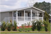 Single-story senior living facility with a covered front porch, white railings, and landscaped lawn.