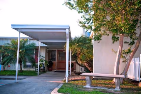 Exterior view of Waldon Health Care Center with entrance canopy, bench, and palm trees.