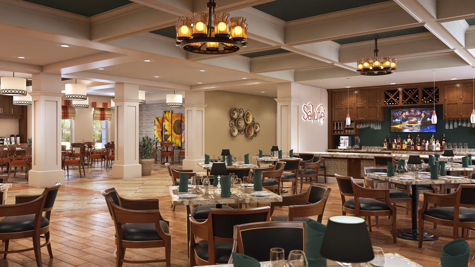 Spacious dining area with multiple tables and chairs arranged neatly. The room features warm lighting with chandeliers and pendant lights. There is a bar area with bottles and a TV mounted above it. The walls have decorative elements including a sunflower painting and a wall art piece. The space has a cozy and inviting atmosphere.