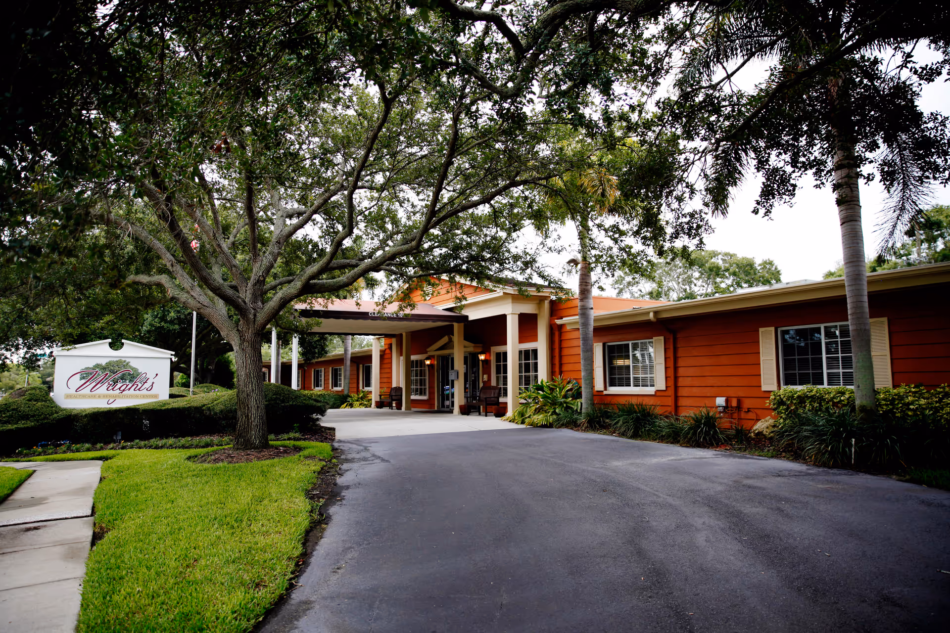View of the exterior entrance of Wright's Healthcare & Rehabilitation Center surrounded by greenery.