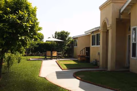 Exterior view of Eternal Life Assisted Living showing a sunny courtyard with seating and walkways.