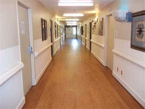A long hallway inside a senior living facility with framed wall art.