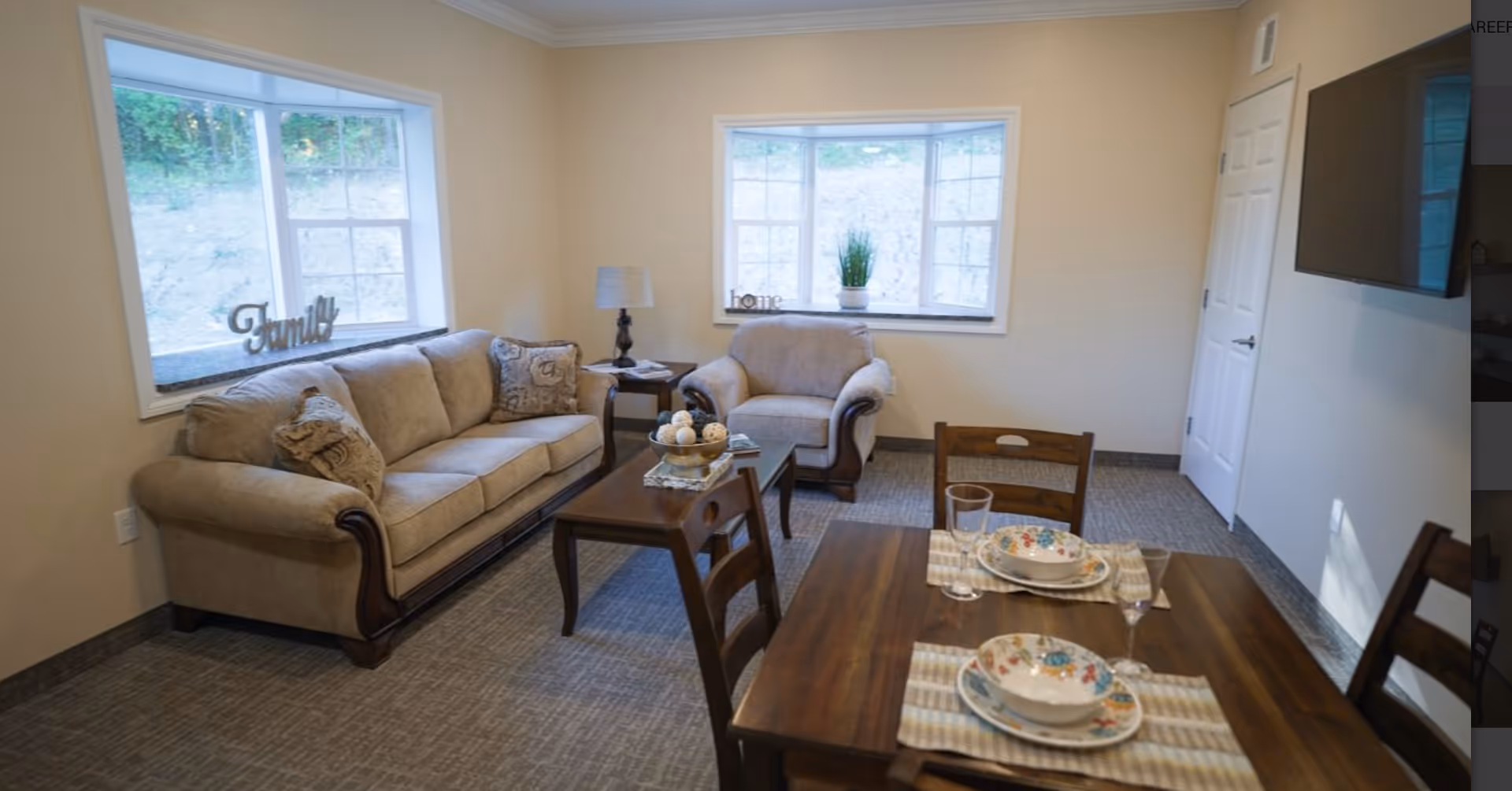 Bright living room with a sofa, armchair, coffee table and a dining table set near two windows.