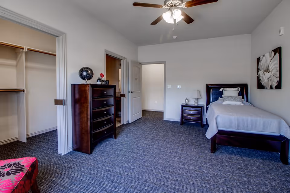 Furnished bedroom with a single bed, nightstand, tall dresser, open closet, ceiling fan, and carpeted floor.