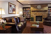 Furnished common room with leather sofas, a coffee table, lamps, and a fireplace flanked by bookcases.