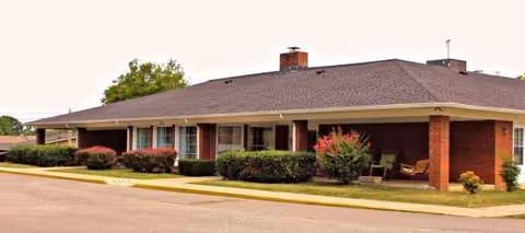 Single-story brick senior living facility with a covered entrance and landscaping.