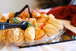 Platter of puff pastry hors d'oeuvres with serving tongs on a table.
