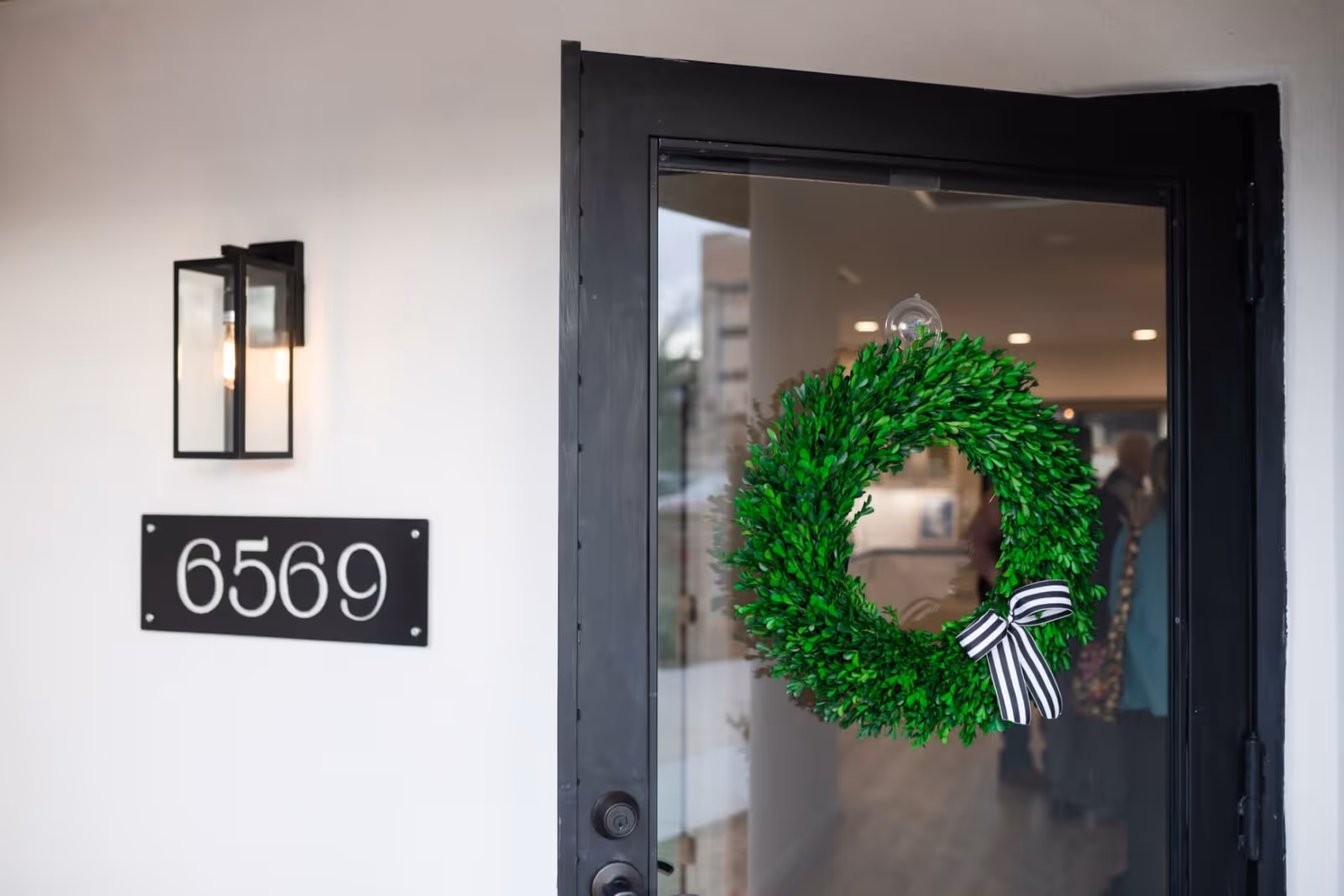 Front door with green wreath and address plaque reading 6569.