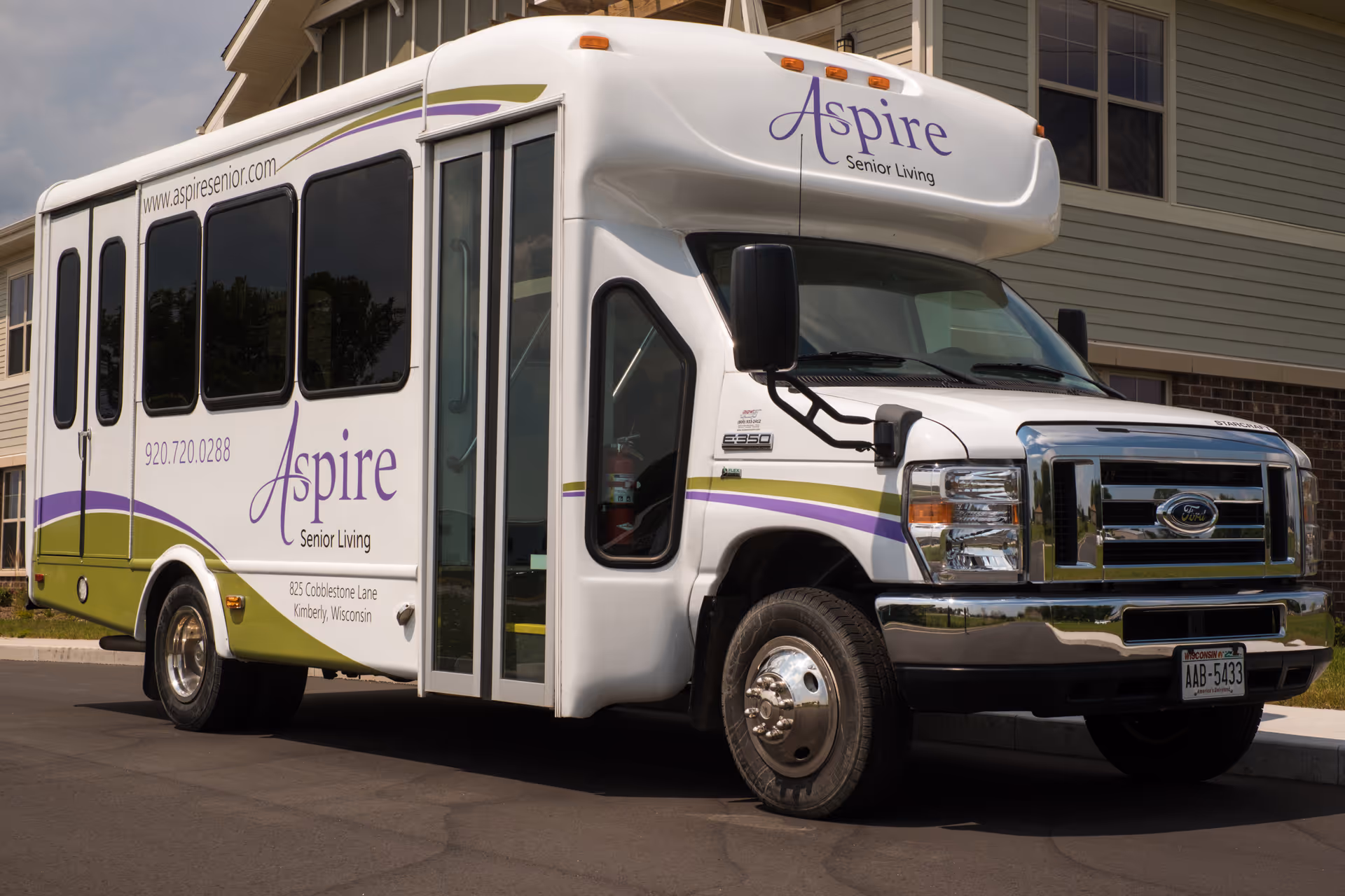 Aspire Senior Living shuttle bus parked in front of a beige, two-story building.