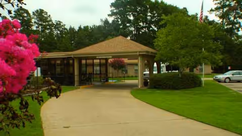 A single-story nursing center building with a covered driveway and manicured landscaping.