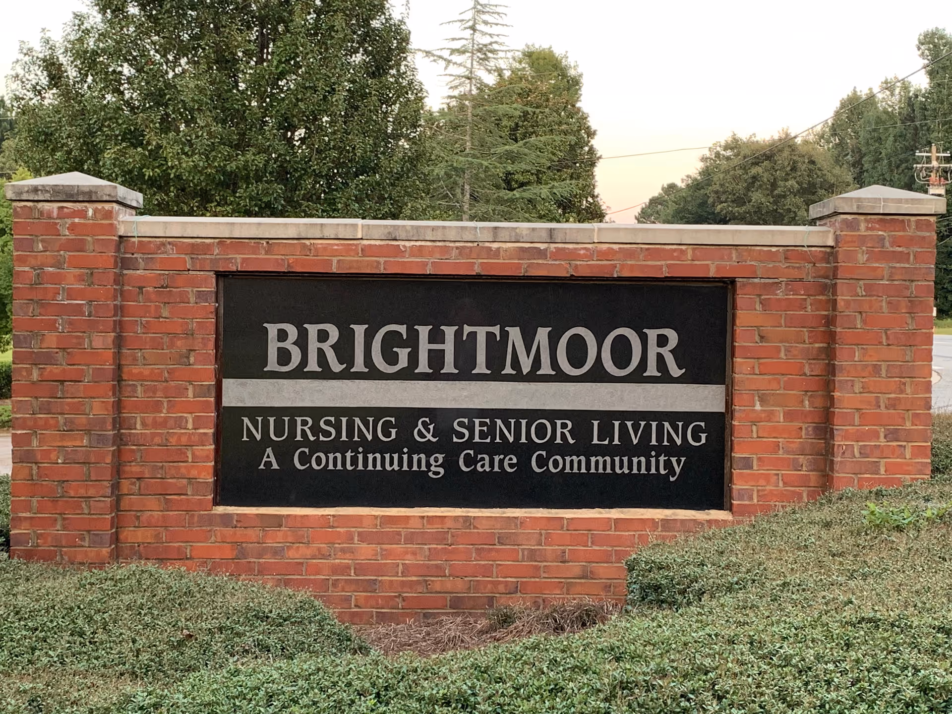 Brick entrance sign reading Brightmoor Nursing & Senior Living set in landscaped grounds with trees behind.