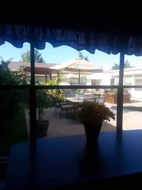 Outdoor patio with tables, chairs, and umbrellas overlooking a courtyard at Mountain View Manor.