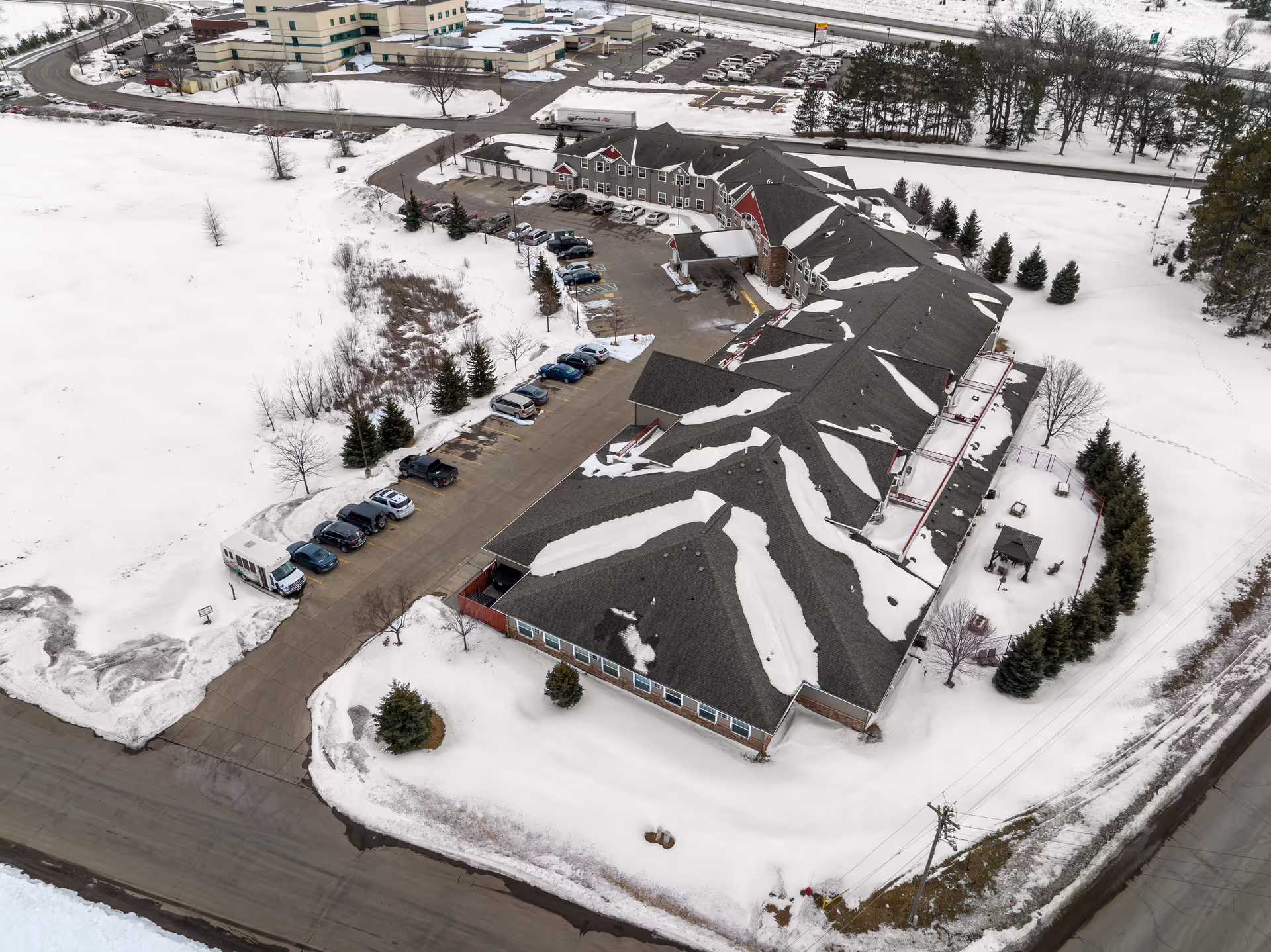 Aerial view of a senior living building and surrounding snow-covered parking lot and grounds.