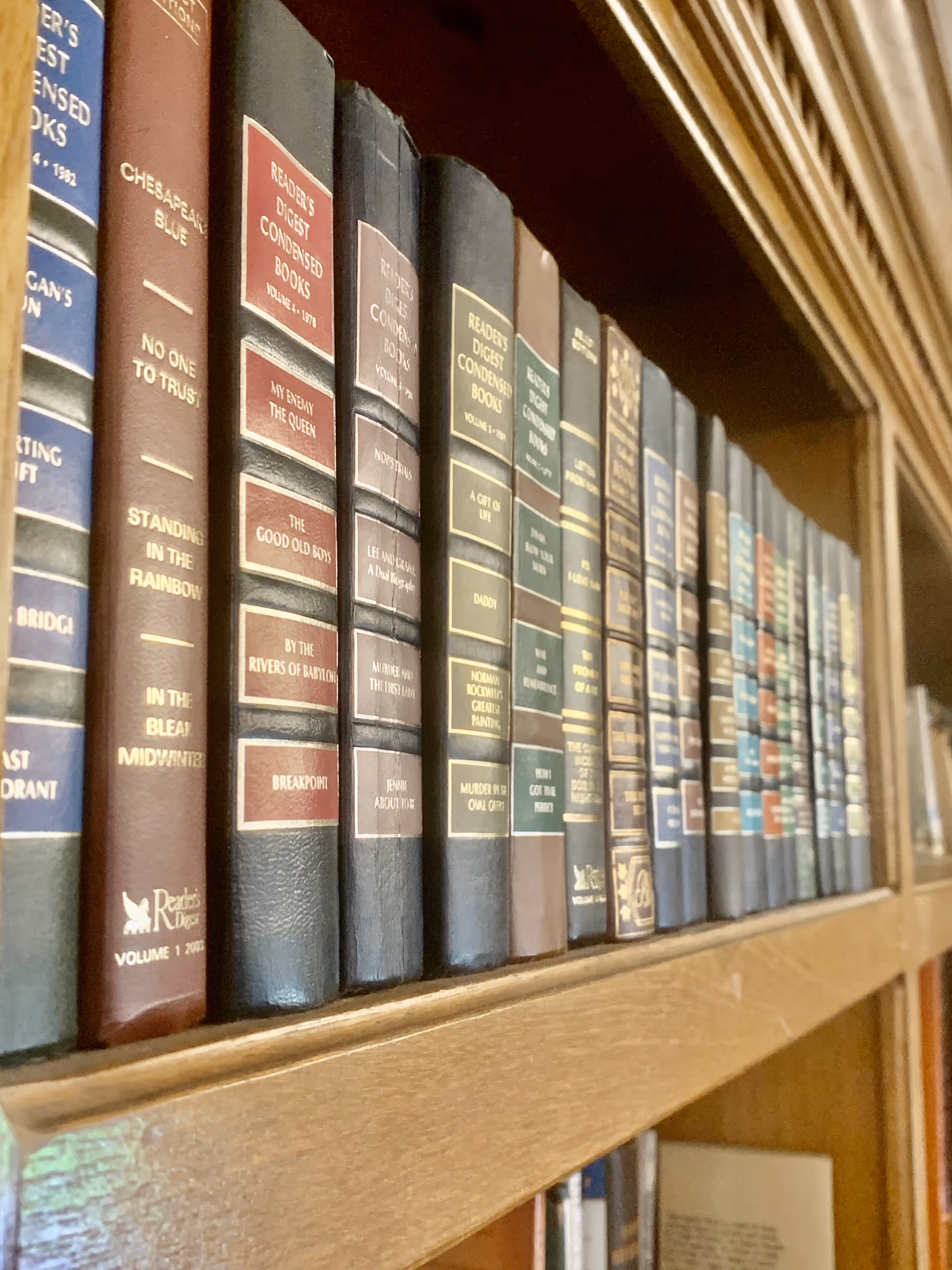 Close-up of a wooden bookshelf lined with leather-bound Reader's Digest condensed books.