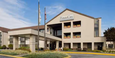 Exterior view of Future Care Canton Harbor facility with entrance, flags, and landscaping.