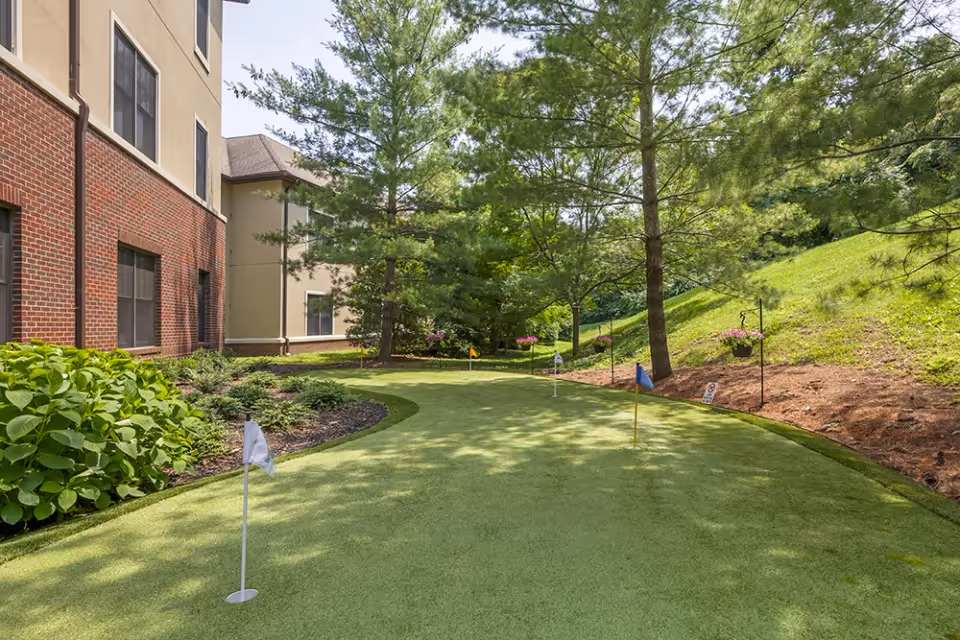 A well-maintained putting green surrounded by lush greenery and trees at Brookdale Green Hills Cumberland.