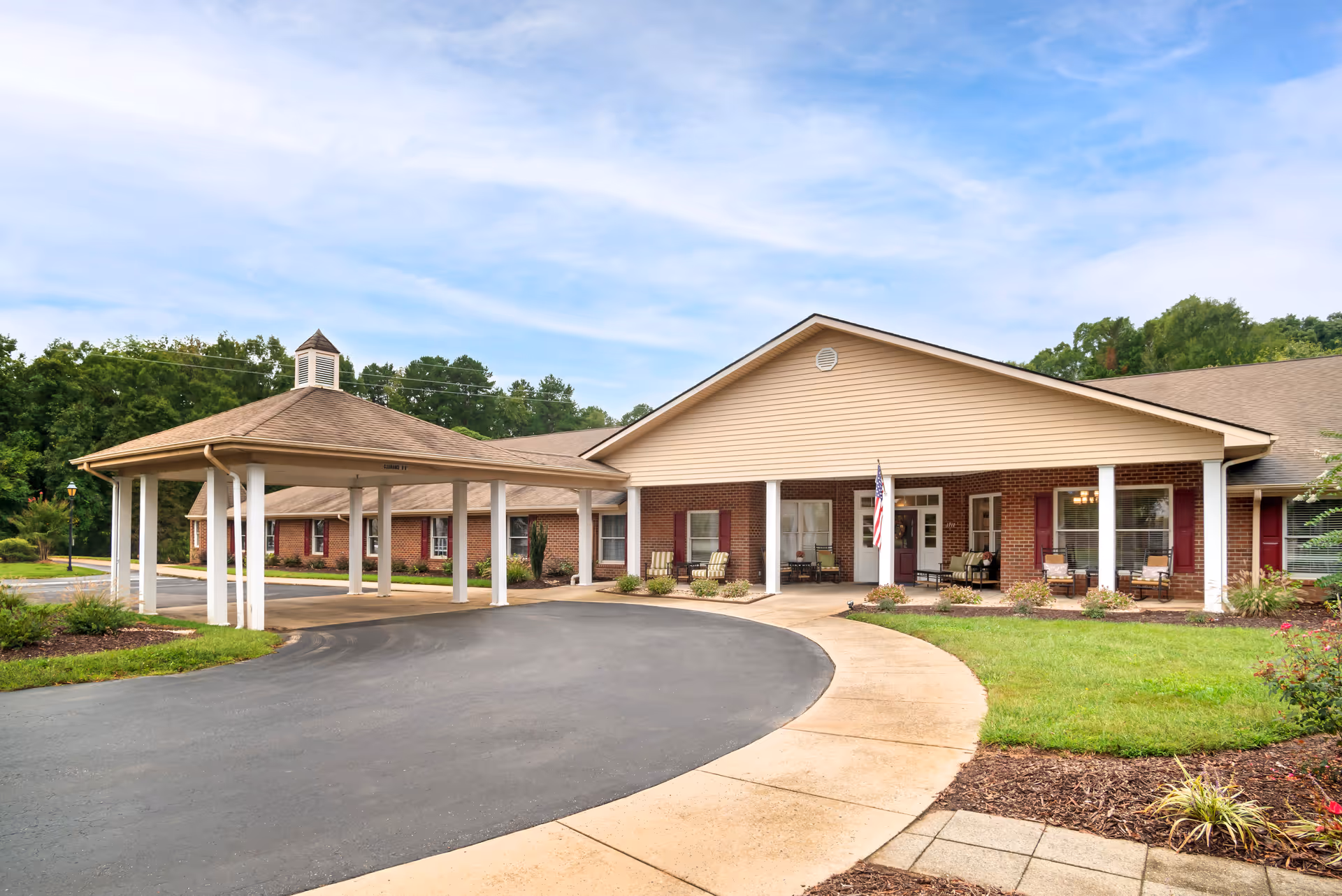 Single story senior living facility with brick facade, circular driveway, and covered entrance.
