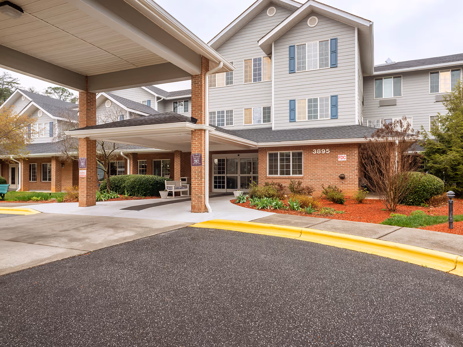 Creekside Terrace senior living building exterior with entrance, brick pillars, and manicured landscaping.