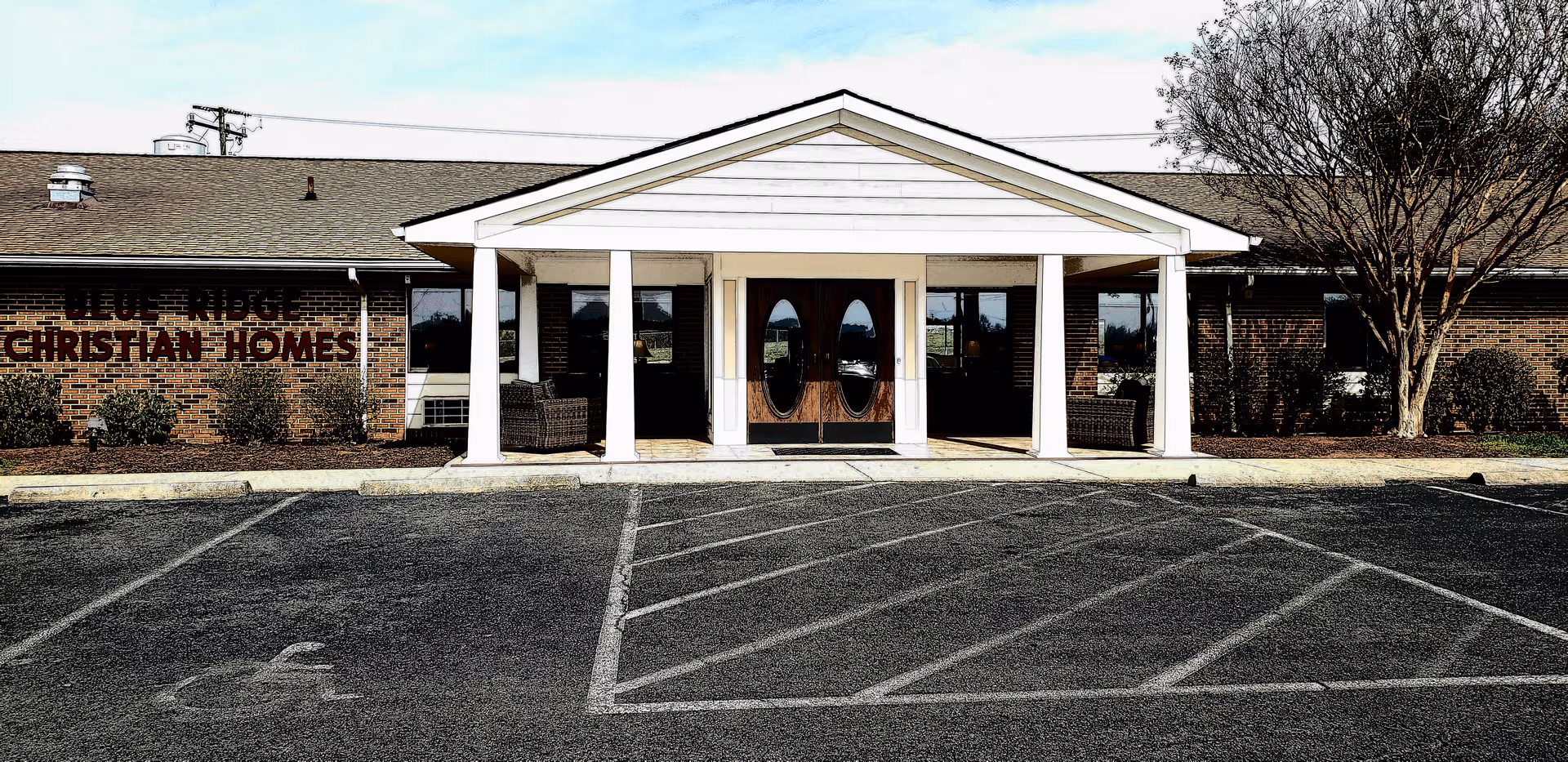 Front entrance of a brick senior living building labeled Blue Ridge Christian Homes with a covered portico and empty parking spaces.