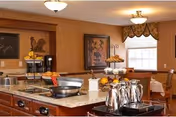 Communal dining area with a central serving island, coffee urns, table settings and warm lighting.