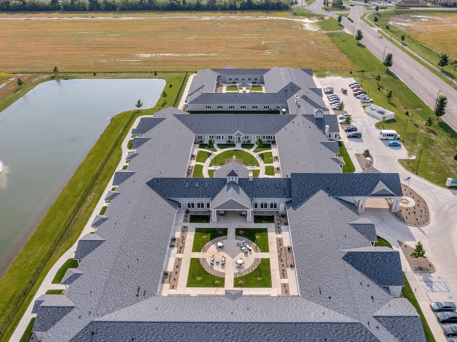 Aerial view of Cedarhurst Senior Living of Newburgh showing a U-shaped building complex with landscaped central courtyards, a parking area and a pond.