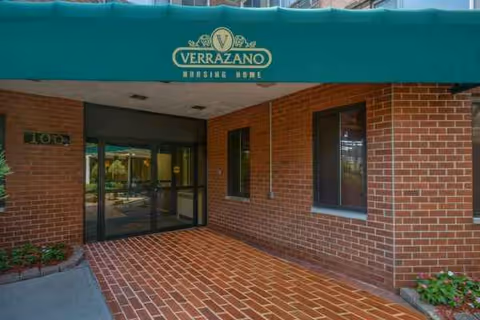 Brick entrance to Verrazano Nursing and Post-Acute Center with glass doors and green canopy.