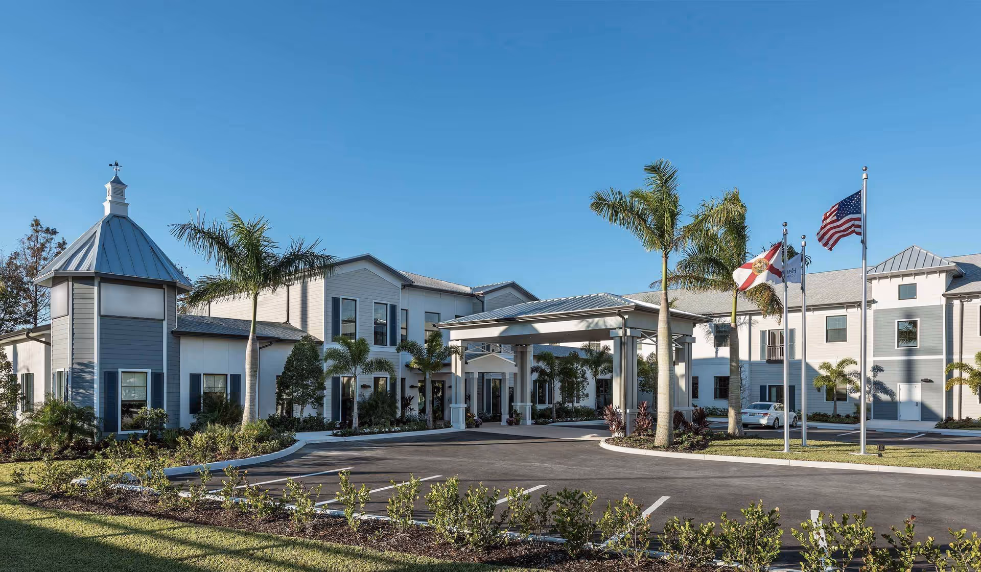 The Harrison of Stuart Assisted Living building exterior with entrance canopy and palm trees.