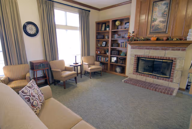 Bright living room with a sofa, armchairs, a fireplace and a built-in bookshelf.