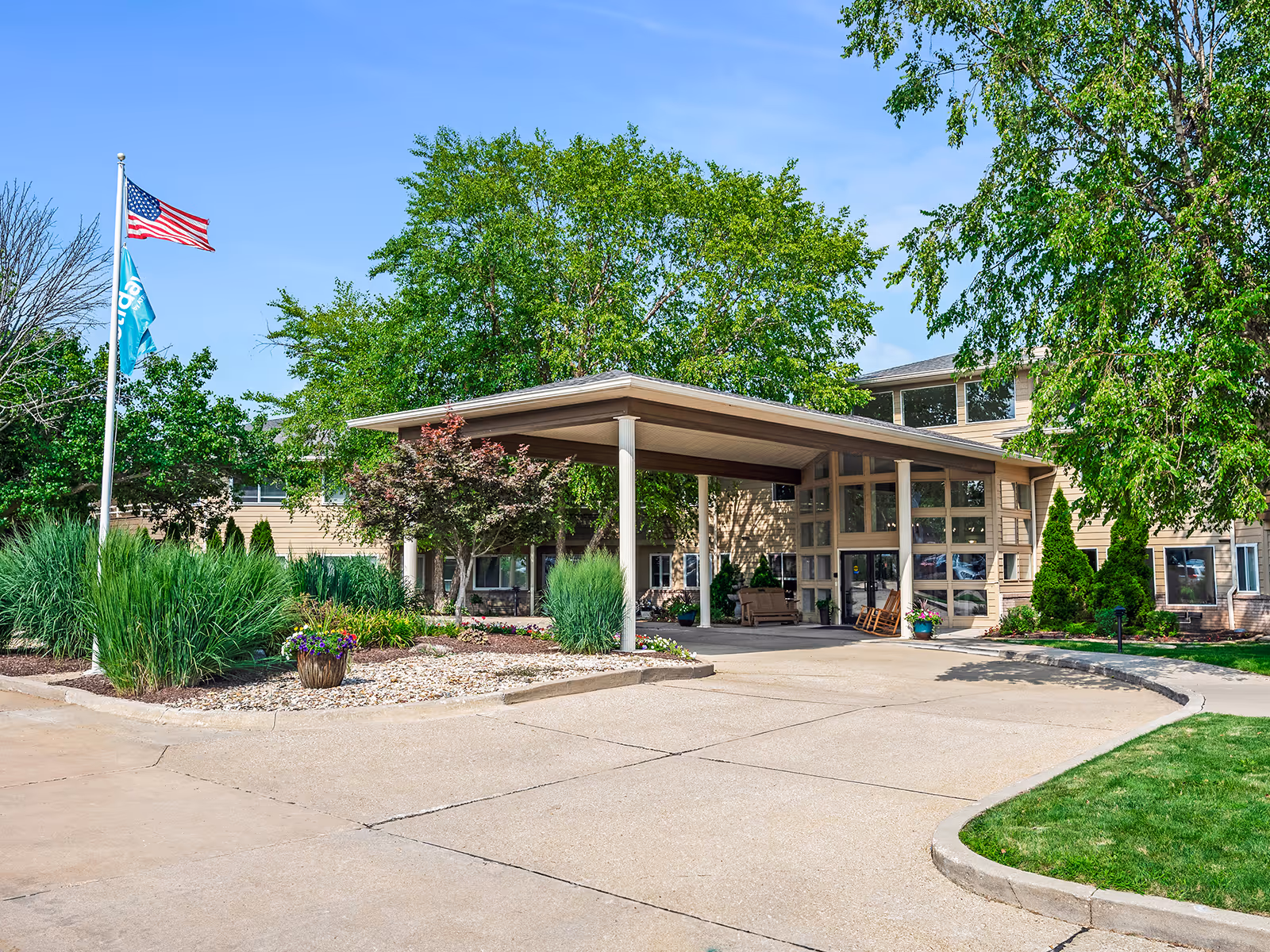 Exterior view of Holiday Palmer Hills entrance with a canopy, flag, and landscaped grounds.